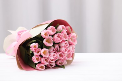 Beautiful bouquet of fresh pink tulips on white wooden table indoors. Space for text