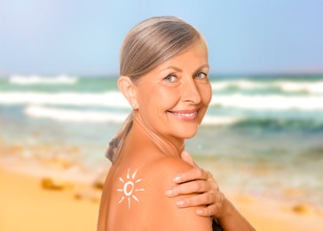 Image of Sun protection. Beautiful young woman with sunblock on her back near sea