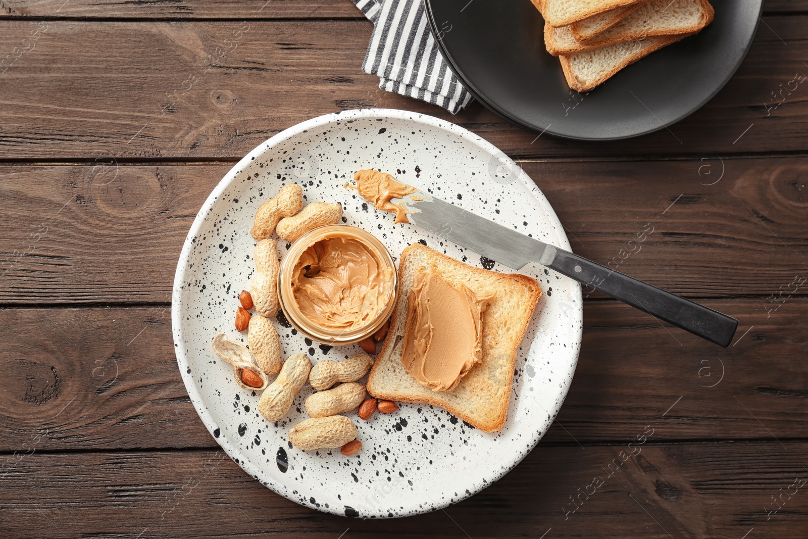 Photo of Jar with creamy peanut butter and toast on plate