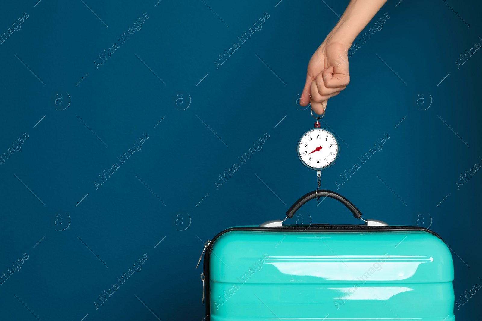 Photo of Woman weighing suitcase against color background, closeup. Space for text