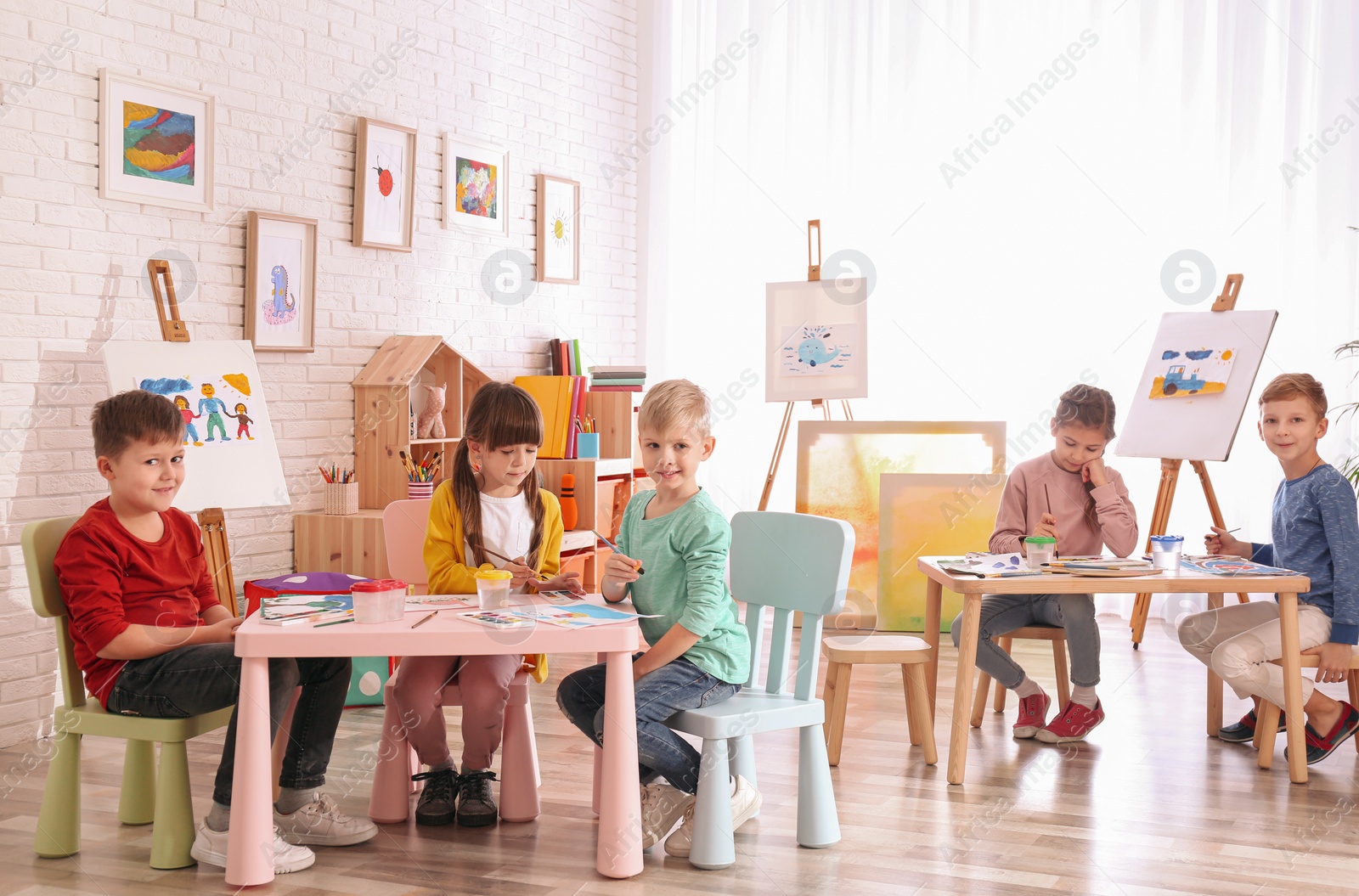 Photo of Cute little children painting at table in room