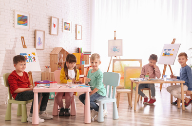 Cute little children painting at table in room