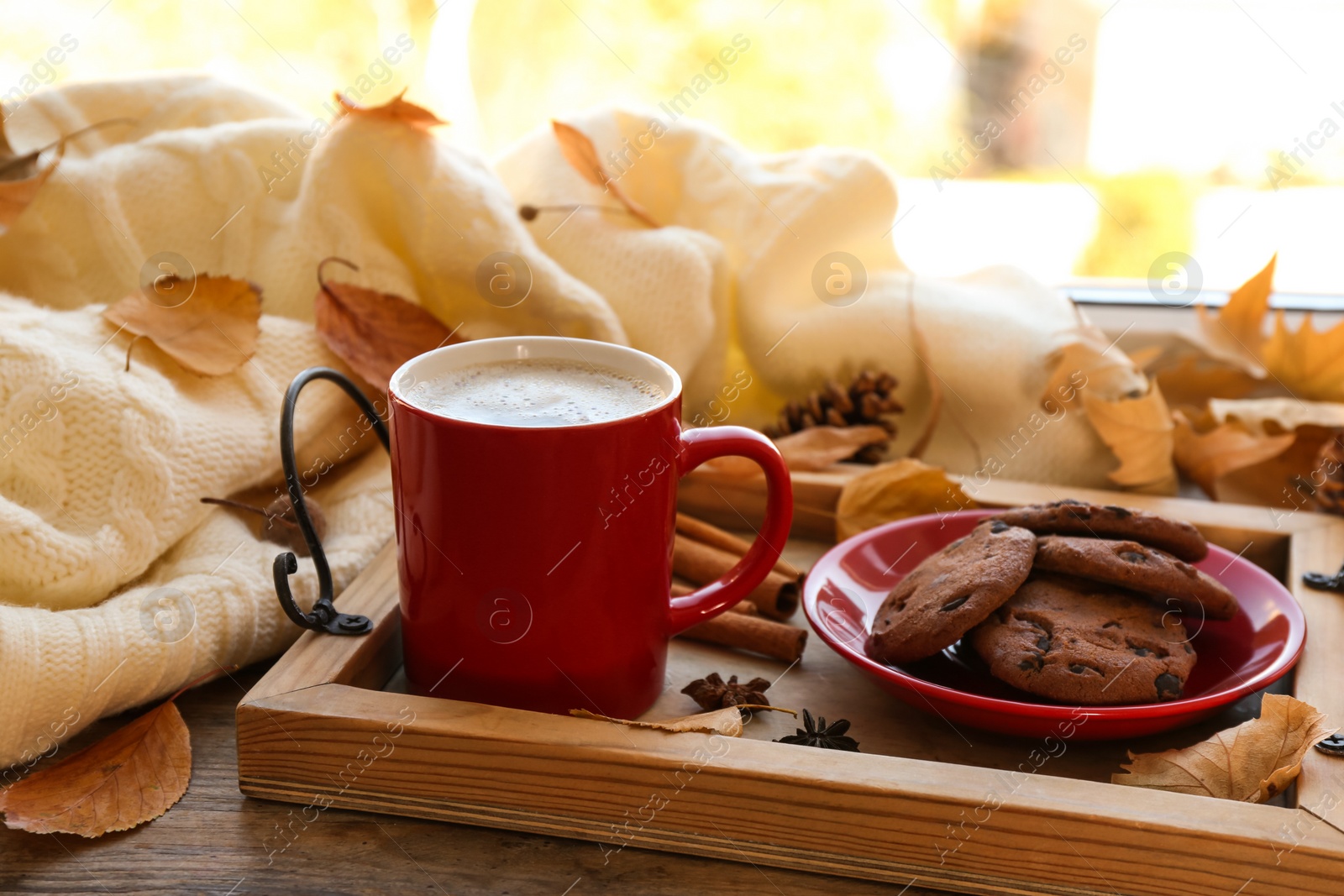 Photo of Composition with cup of hot drink, sweater and autumn leaves on windowsill. Cozy atmosphere