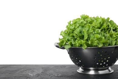 Photo of Metal colander with fresh lettuce on black textured table against white background, space for text