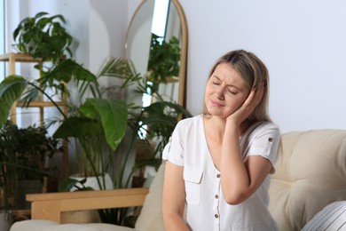 Photo of Young woman suffering from ear pain at home. Space for text
