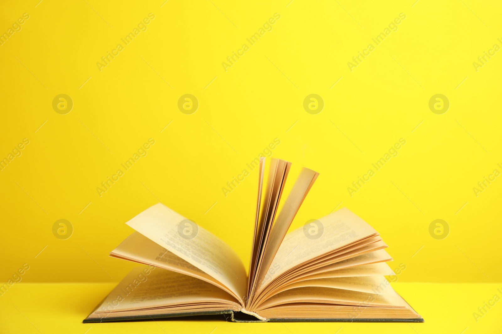 Photo of Open old hardcover book on yellow background. Space for text