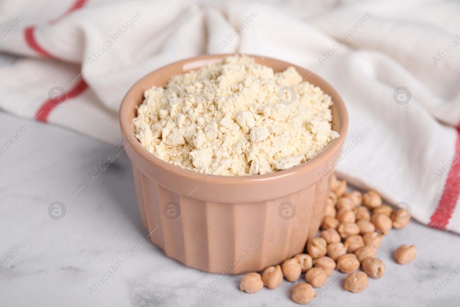 Photo of Chickpea flour in bowl and seeds on white marble table