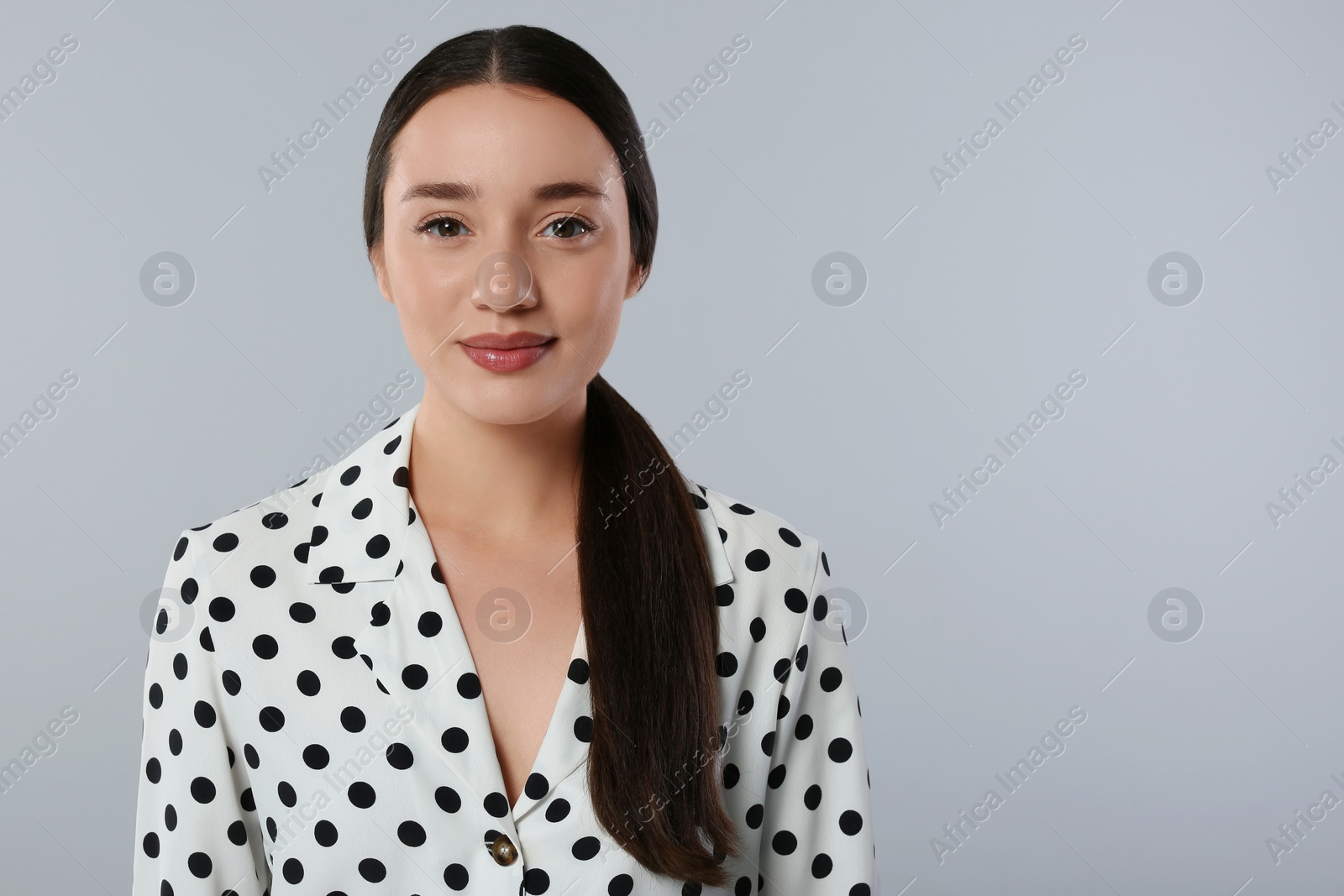 Photo of Portrait of beautiful young woman in stylish blouse on light grey background. Space for text