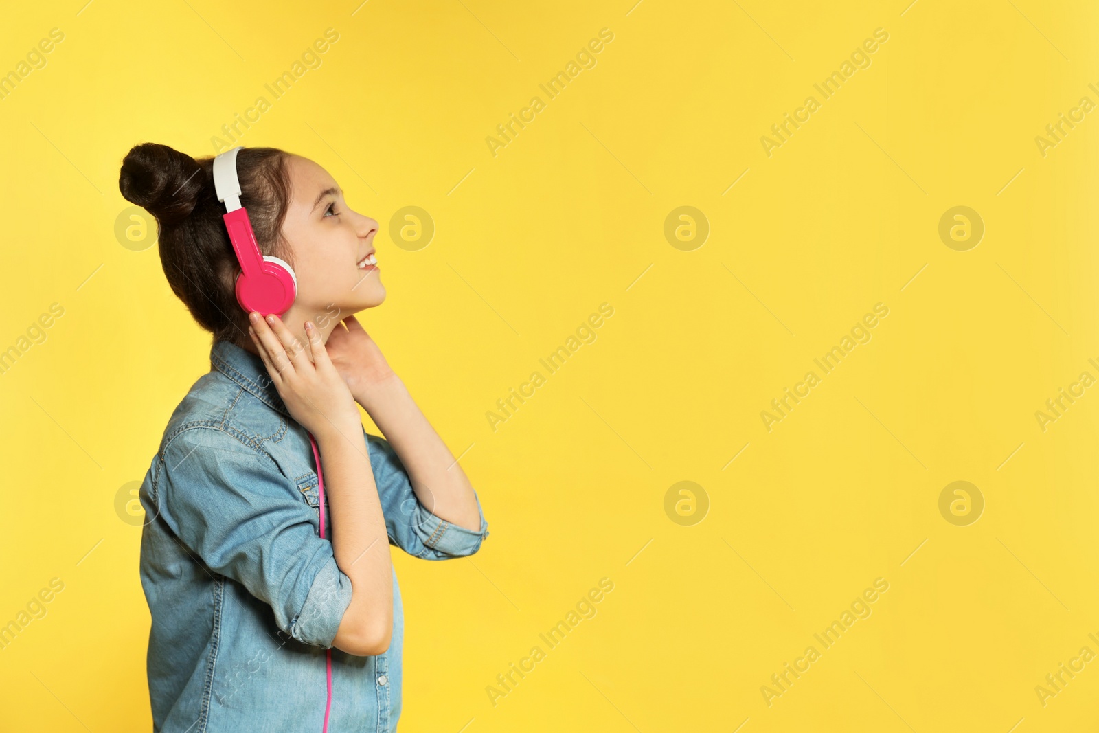 Photo of Cute girl enjoying music in headphones on color background. Space for text