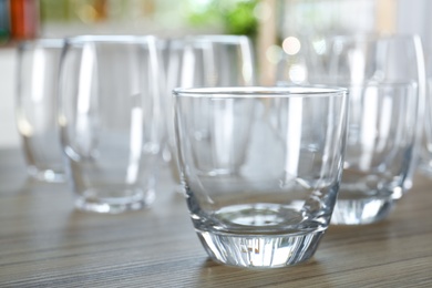 Photo of Empty glasses on wooden table against blurred background