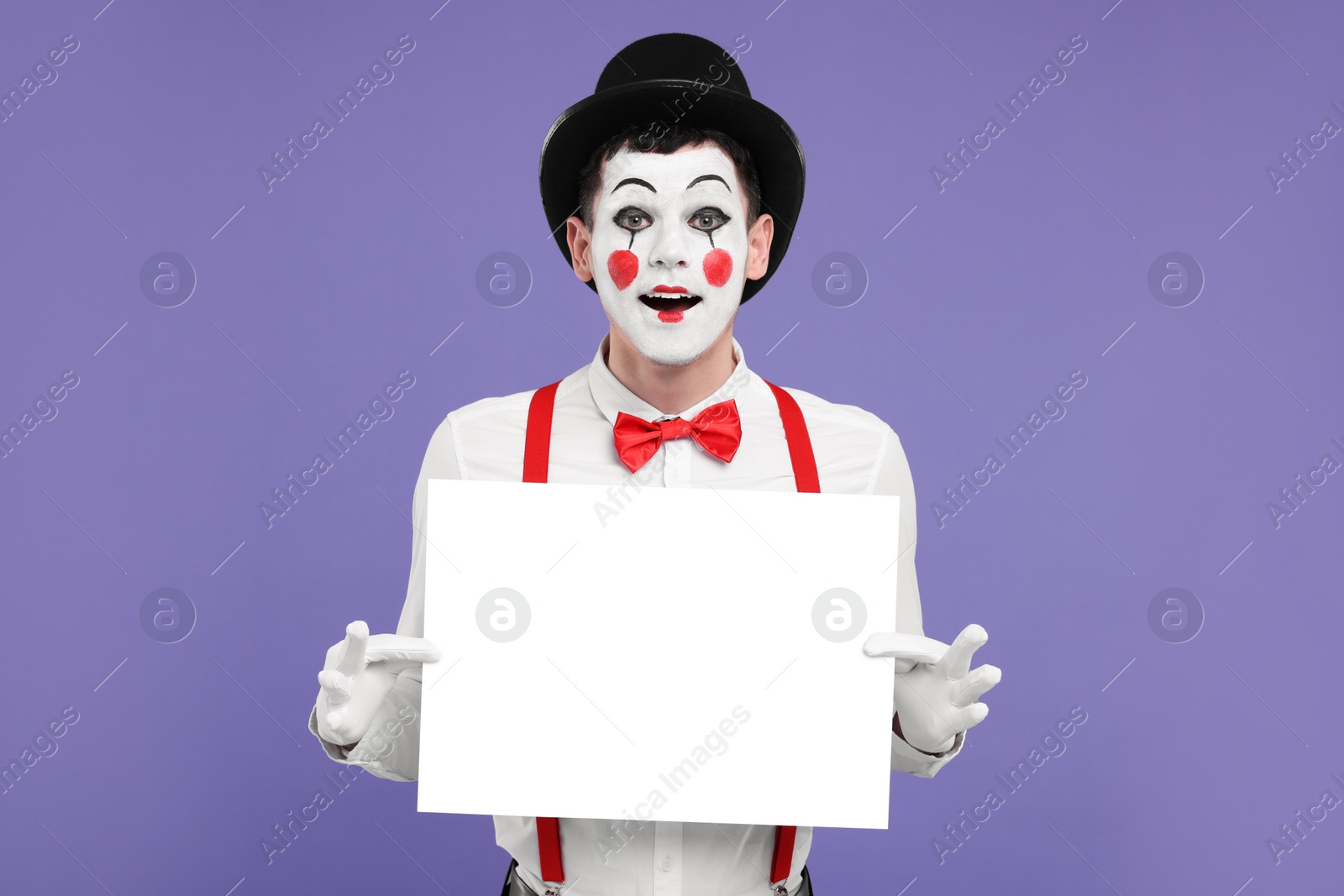 Photo of Funny mime artist with blank sign on purple background