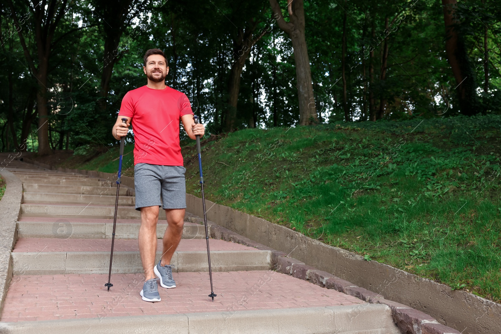 Photo of Man practicing Nordic walking with poles on steps outdoors. Space for text