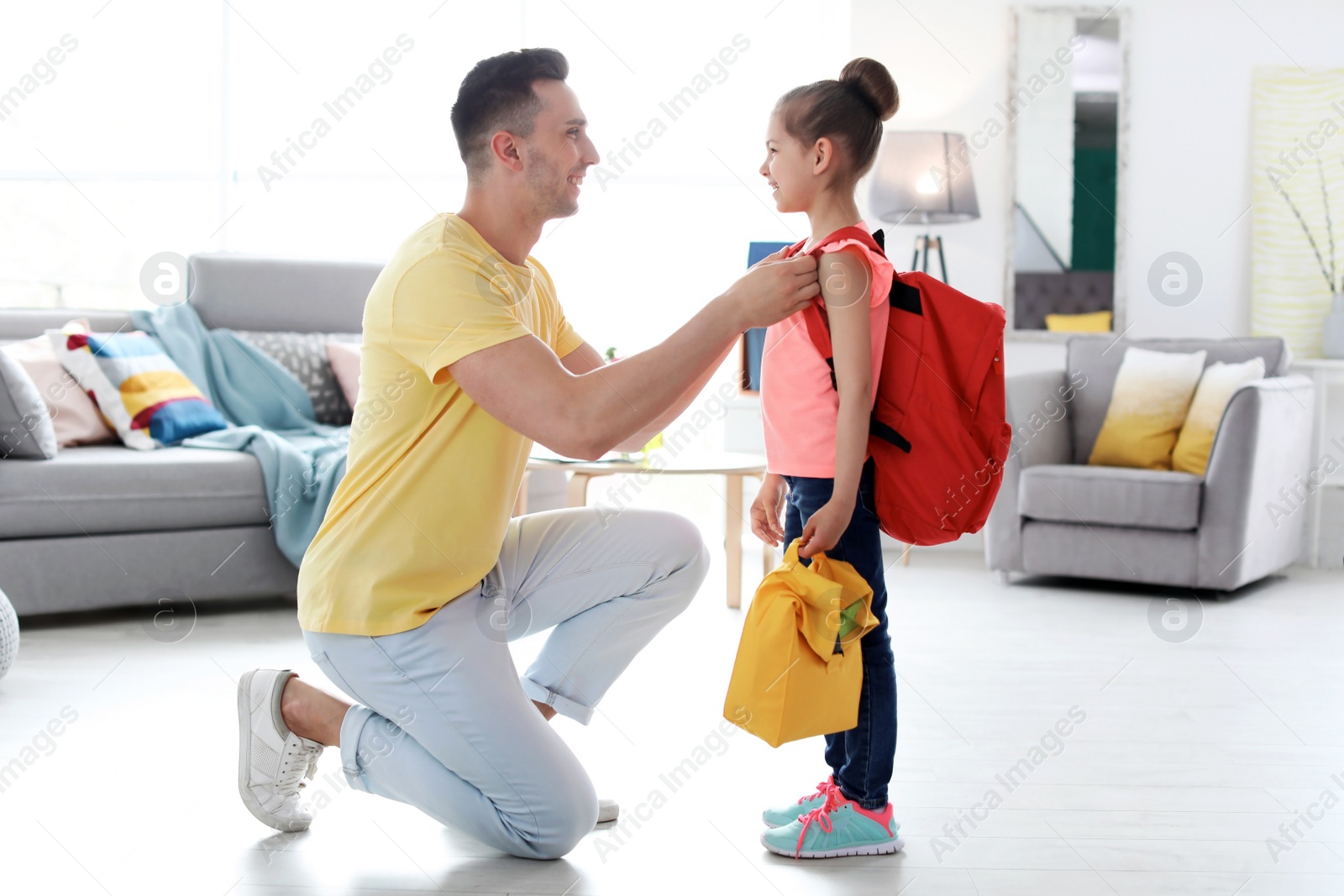 Photo of Young man helping his little child get ready for school at home