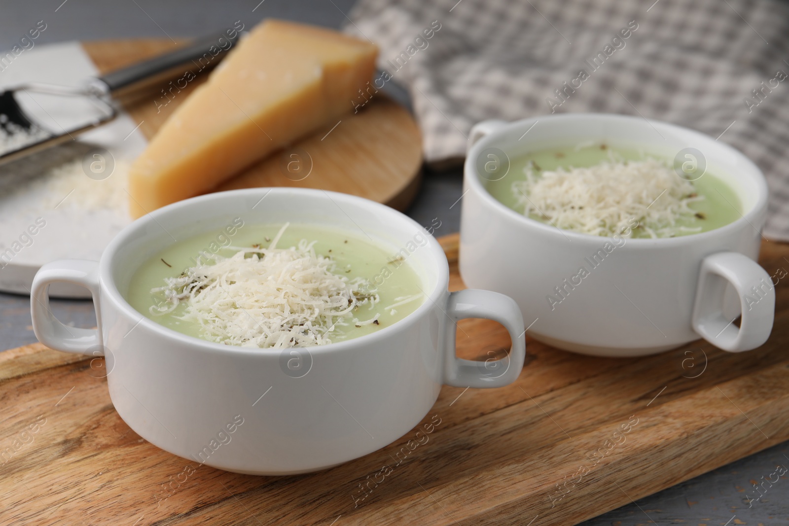 Photo of Delicious cream soup with parmesan cheese in bowls on table