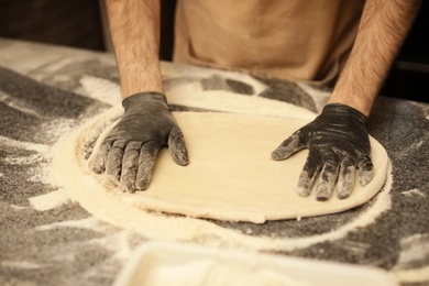 Photo of Man making pizza at table, closeup view