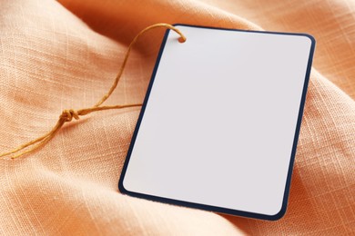 Photo of Cardboard tag with space for text on pale orange fabric, closeup