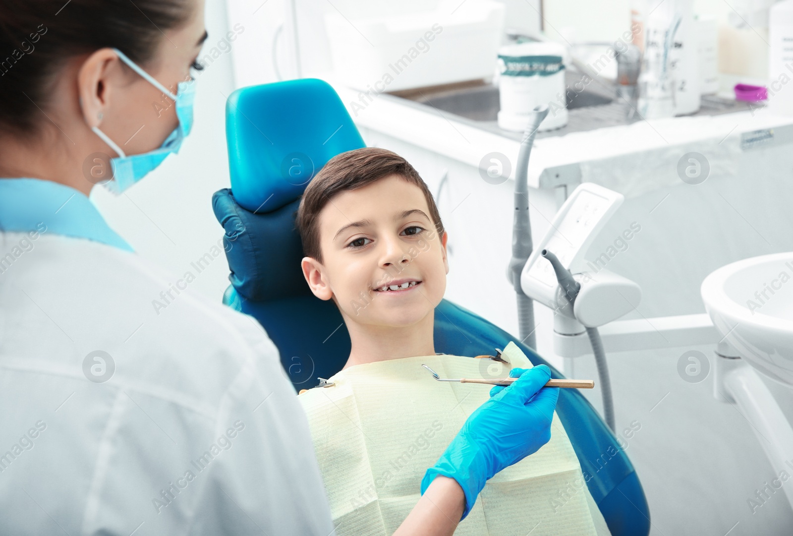 Photo of Professional dentist working with little patient in modern clinic