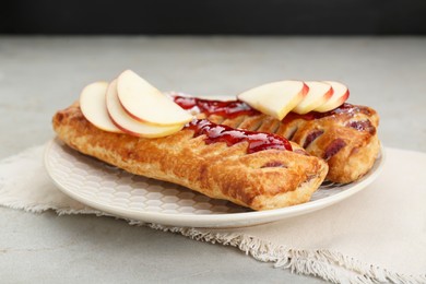 Fresh tasty puff pastry with jam and apples on white textured table, closeup