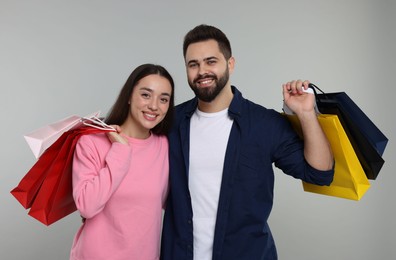 Happy couple with shopping bags on grey background