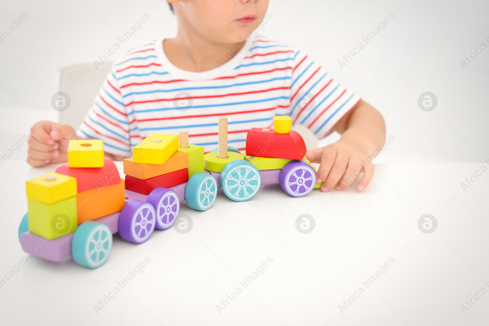 Photo of Little boy playing with toy at white table, closeup