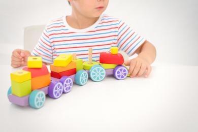 Photo of Little boy playing with toy at white table, closeup