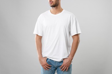 Photo of Man wearing white t-shirt on gray background, closeup