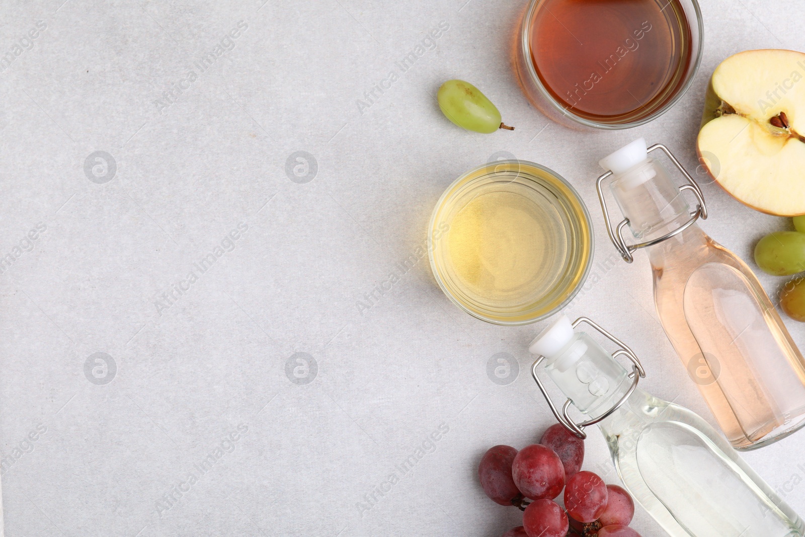 Photo of Different types of vinegar and ingredients on light table, flat lay. Space for text