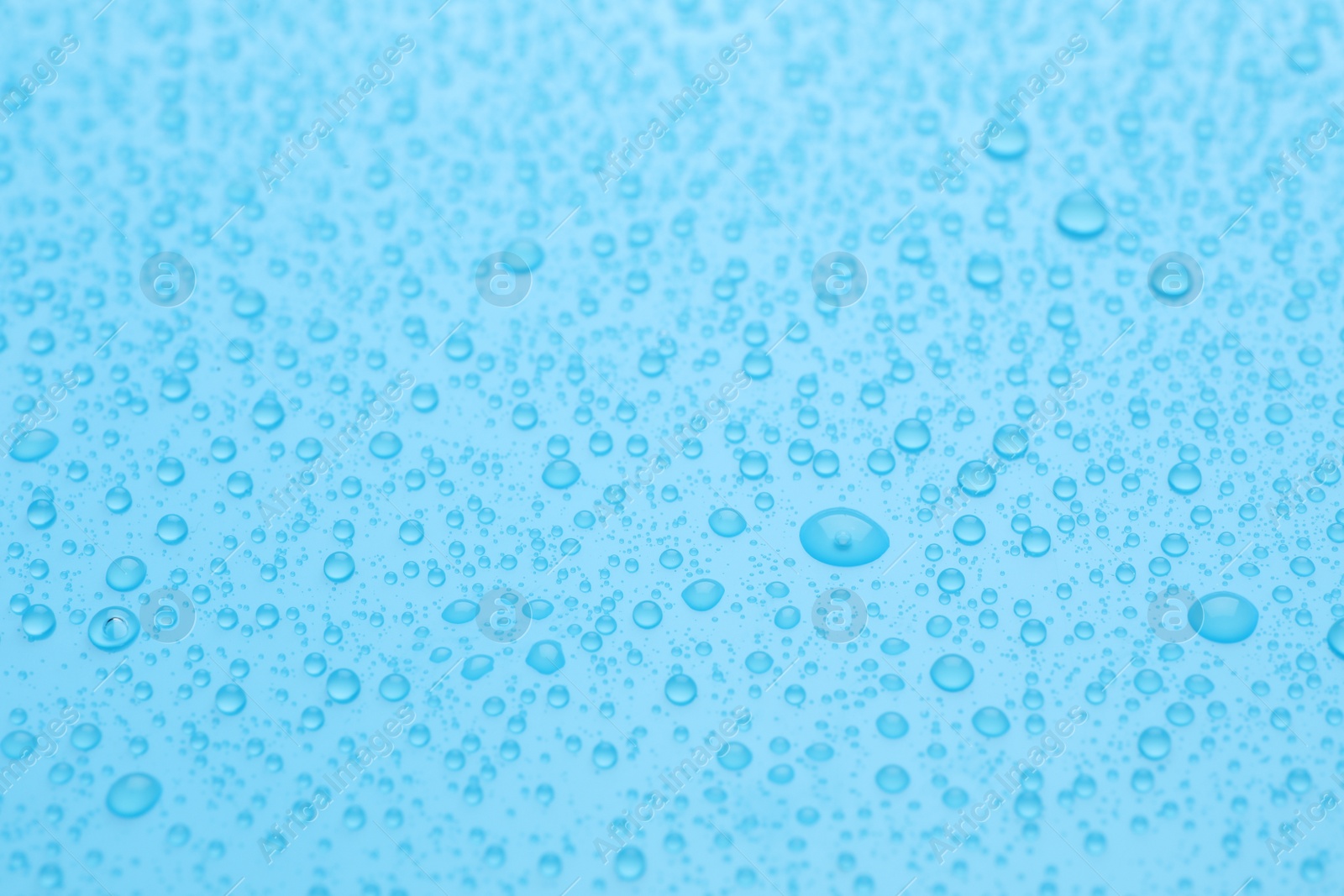 Photo of Water drops on light blue background, closeup view