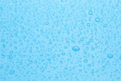 Water drops on light blue background, closeup view