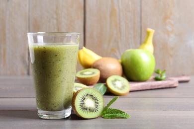 Photo of Delicious kiwi smoothie and fresh fruits on wooden table. Space for text