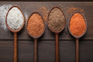 Different kinds of salt on wooden table, flat lay