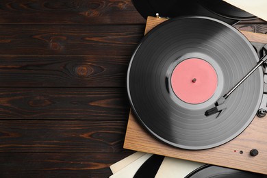 Photo of Modern player and vinyl records on wooden background, flat lay. Space for text