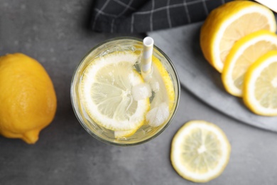 Photo of Soda water with lemon slices and ice cubes on grey table, flat lay