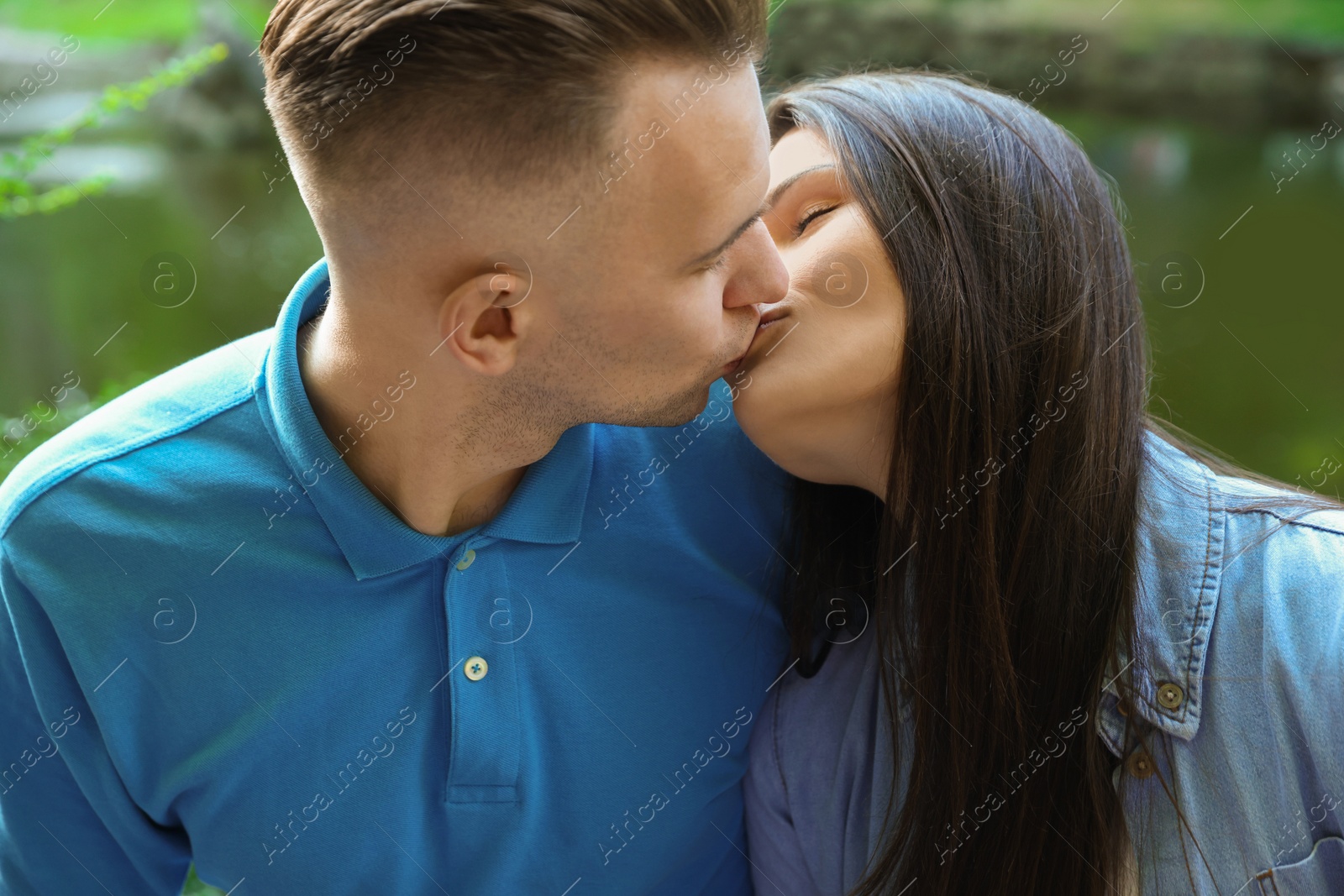 Photo of Affectionate young couple kissing in park, closeup