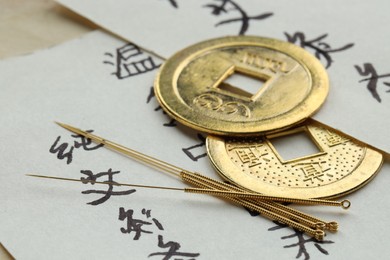 Photo of Acupuncture needles, Chinese coins on sheets of paper with characters, closeup