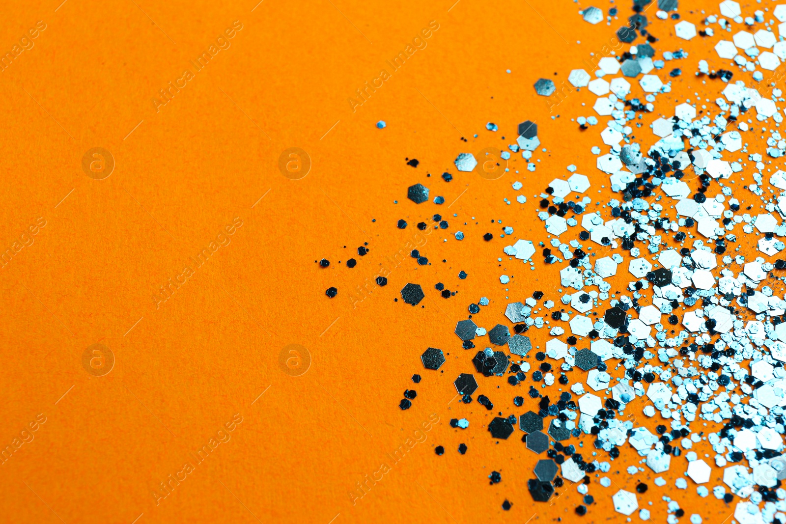 Photo of Shiny bright glitter on orange background. Space for text