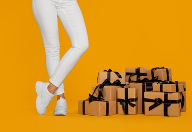 Photo of Woman and gift boxes on yellow background, closeup. Black Friday