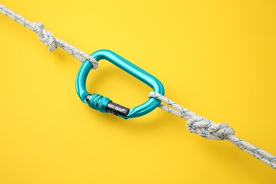 Photo of One metal carabiner with ropes on yellow background