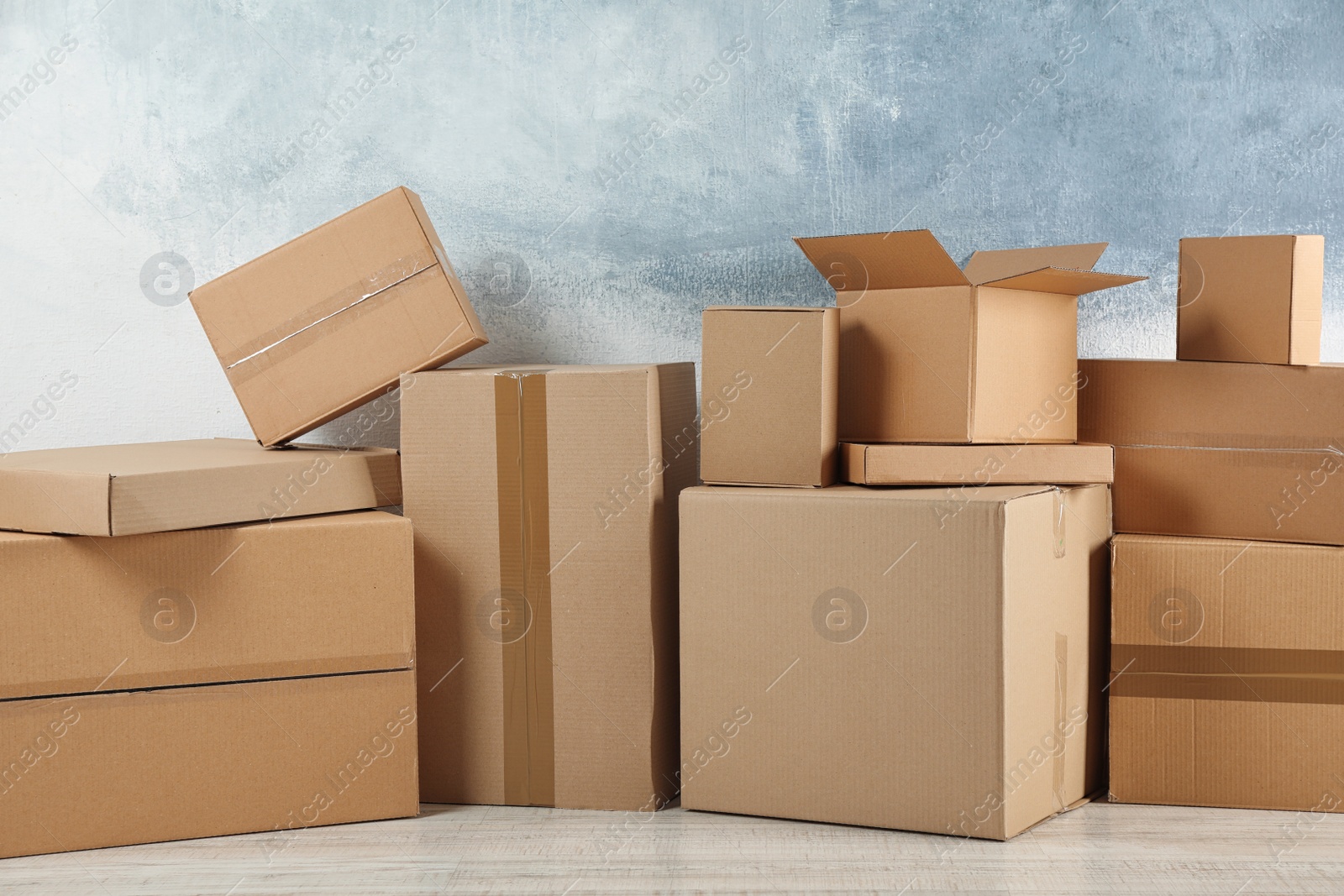 Photo of Pile of cardboard boxes near color wall indoors