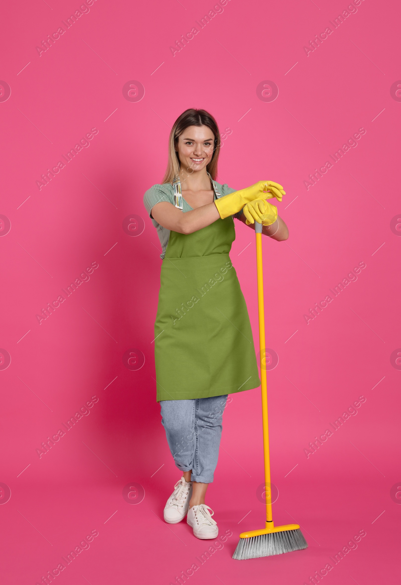 Photo of Young woman with yellow broom on pink background