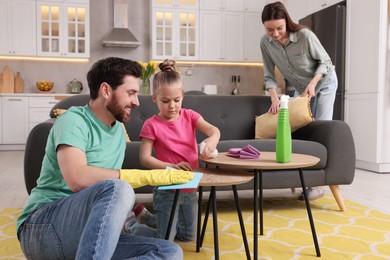 Photo of Spring cleaning. Parents with their daughter tidying up living room together