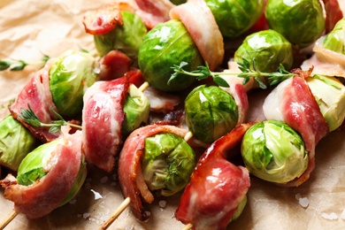 Photo of Skewers with Brussels sprouts and bacon on parchment paper, closeup