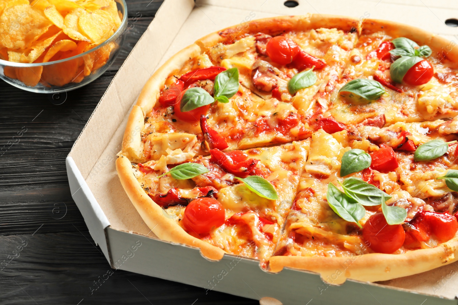 Photo of Delicious pizza with tomatoes and sausages in cardboard box, closeup