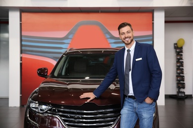 Salesman standing in modern auto dealership. Buying new car