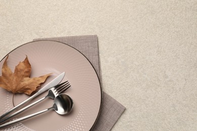 Stylish table setting with cutlery and dry leaf on light surface, top view. Space for text