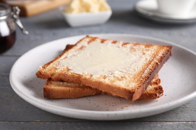 Photo of Tasty toasts with butter served on grey wooden table, closeup