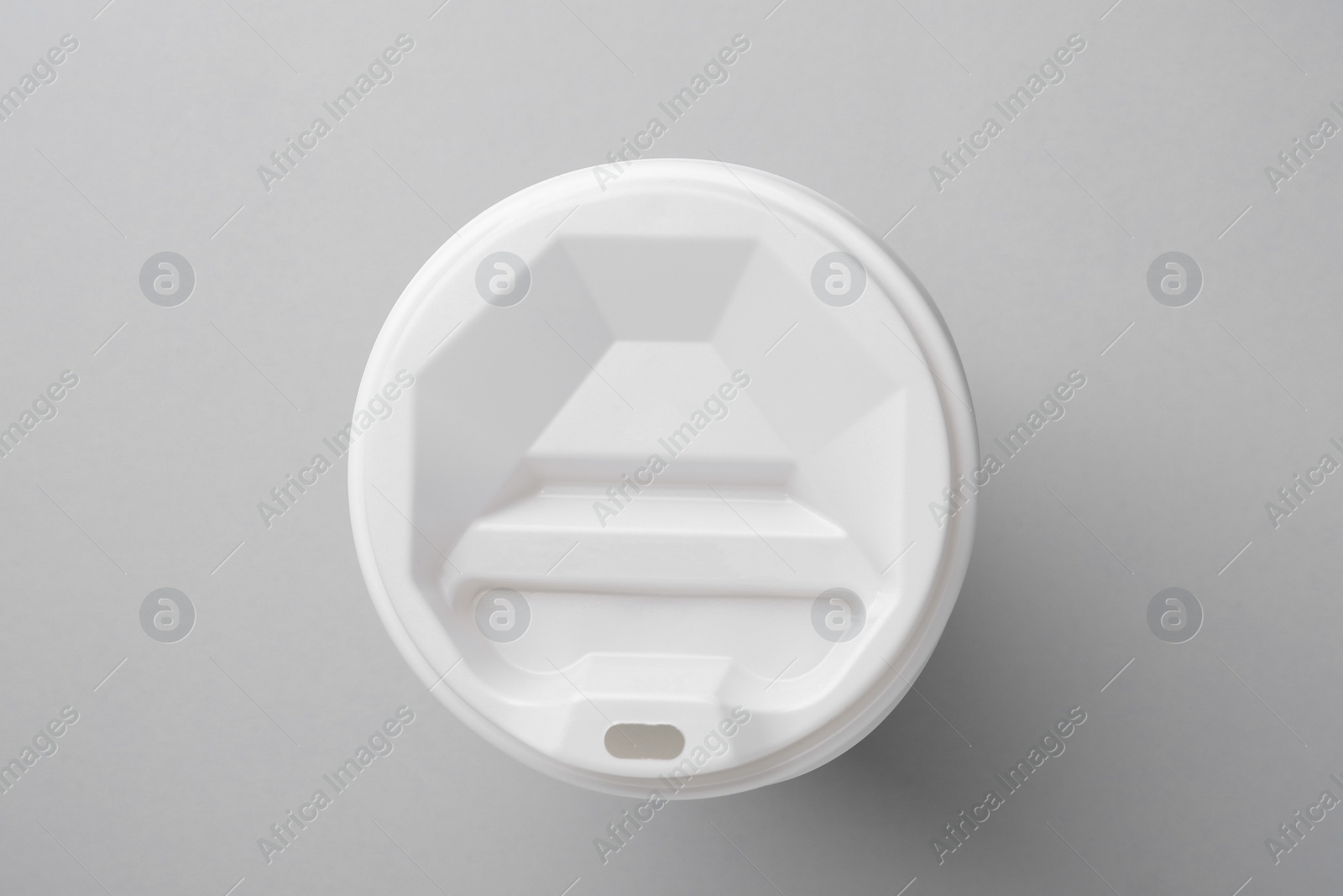 Photo of One paper cup with white lid on light grey background, top view. Coffee to go