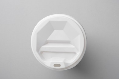 One paper cup with white lid on light grey background, top view. Coffee to go