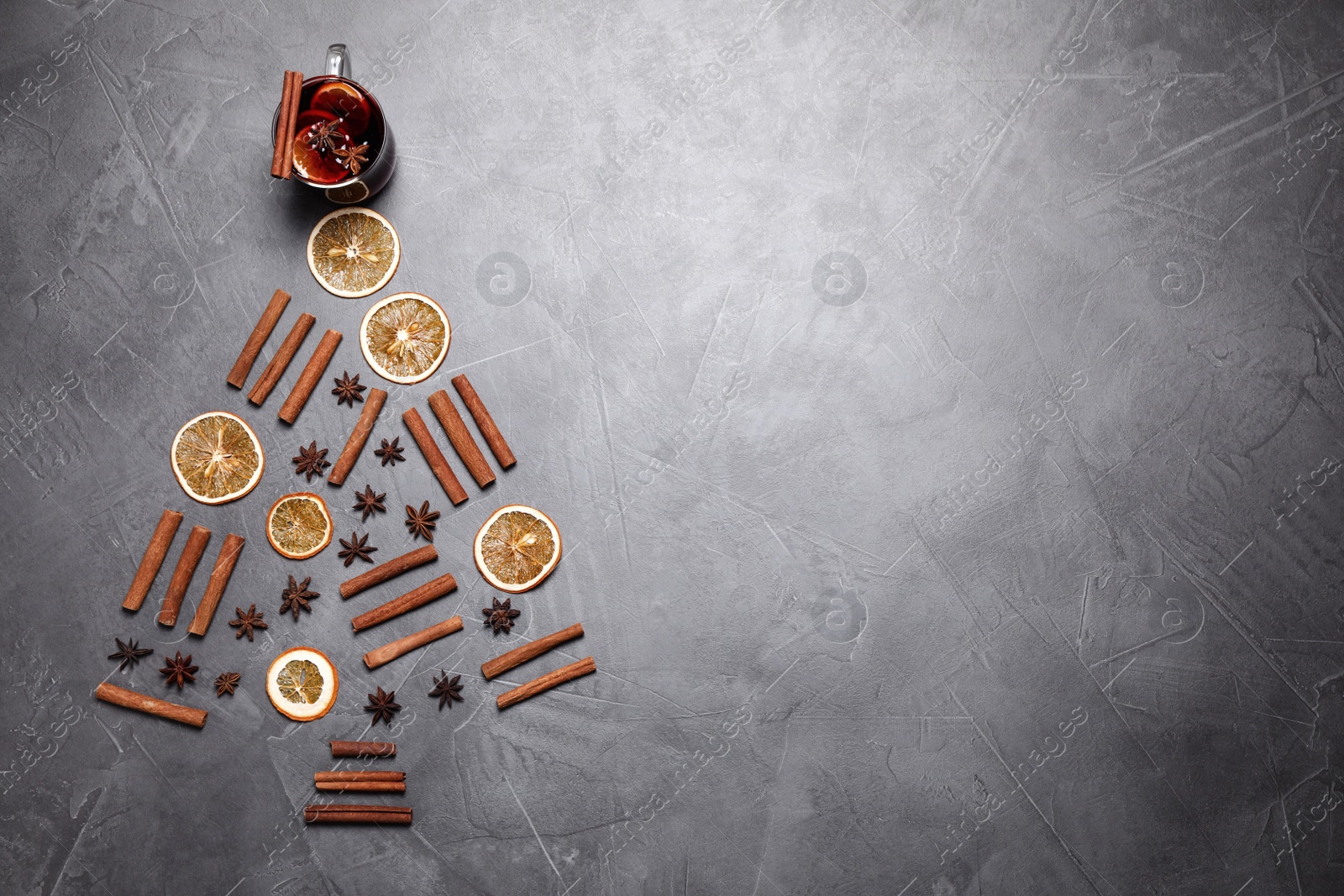 Photo of Flat lay composition with glass of mulled wine on grey table. Space for text