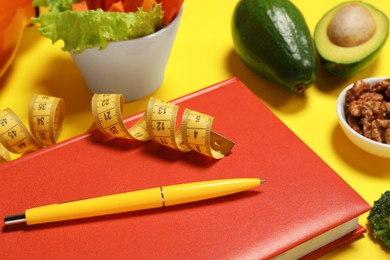 Photo of Weight loss concept. Composition with notebook, measuring tape and different products on yellow background, closeup